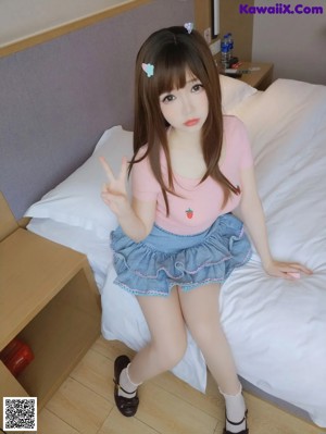 A woman in a pink shirt and white panties sitting on a bed.