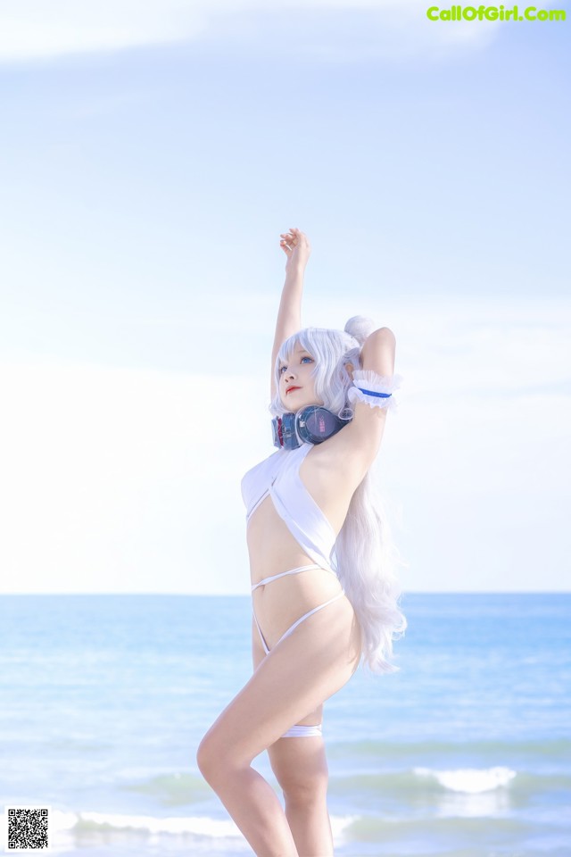 A woman in a white bikini standing on the beach.