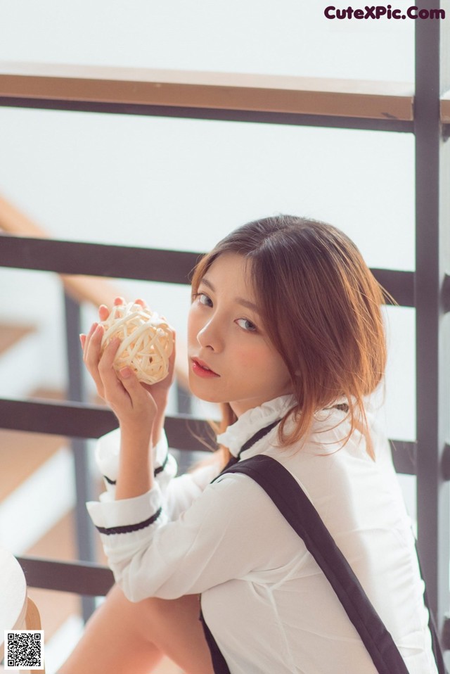 A woman sitting on a chair holding a piece of food.