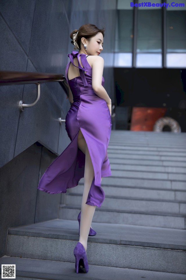 A woman in a purple dress is walking up some stairs.