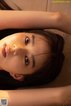 A woman with long brown hair laying on the ground.