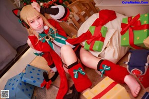 A woman sitting on a bed next to a christmas tree.