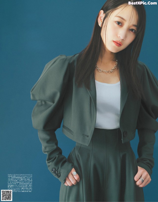 A woman in a green jacket and skirt posing for a magazine.