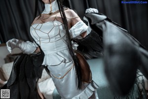 A woman with long black hair wearing a white dress and gloves.