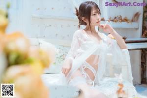 A woman in a white lingerie standing in front of a window.