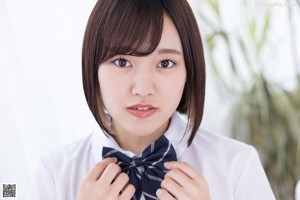 A woman in a school uniform sitting on the floor.