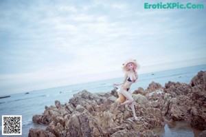 A woman in a white shirt and a cat hat on a beach.