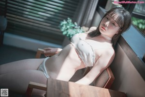 A woman in a white lingerie sitting on a bed.