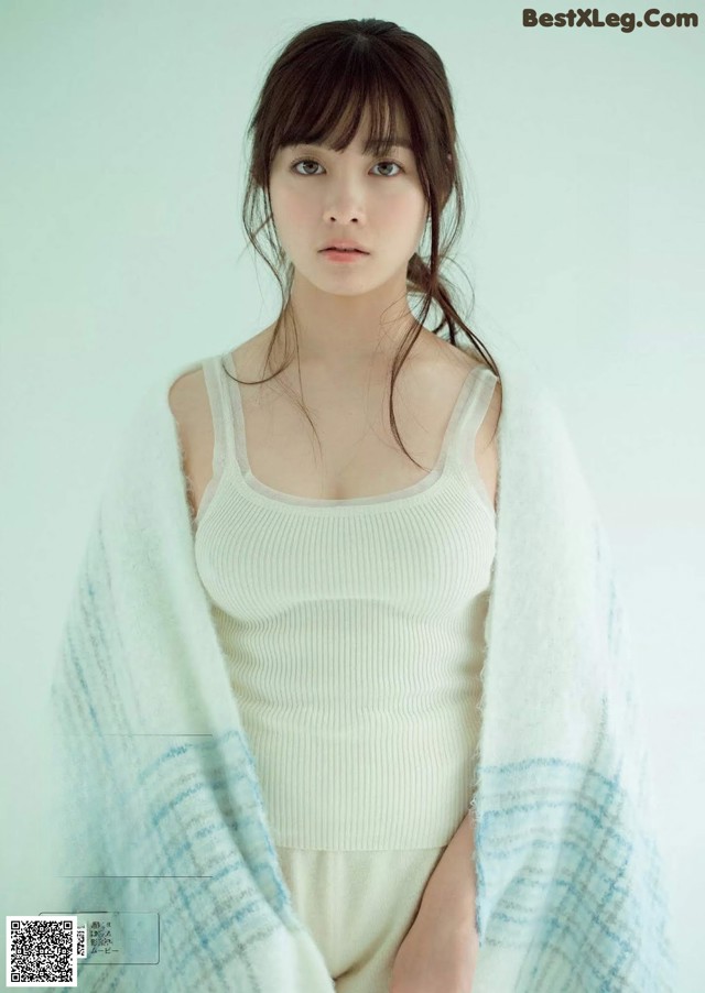 A woman in a white tank top and a blue and white blanket.