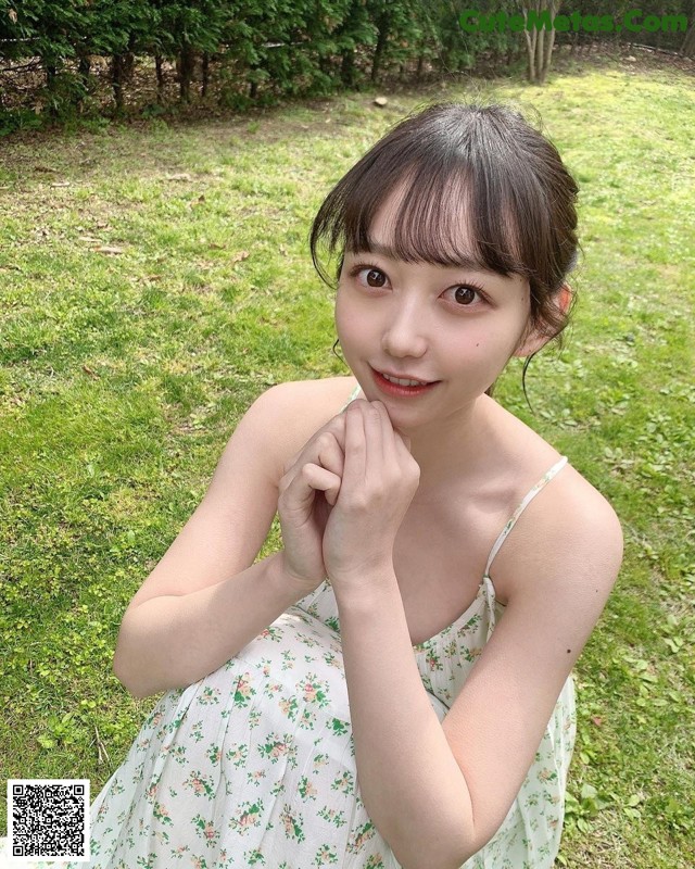 A woman in a white dress sitting in the grass.