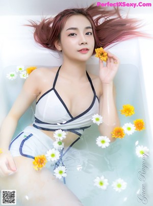 A woman in a bathtub with a flower in her hand.