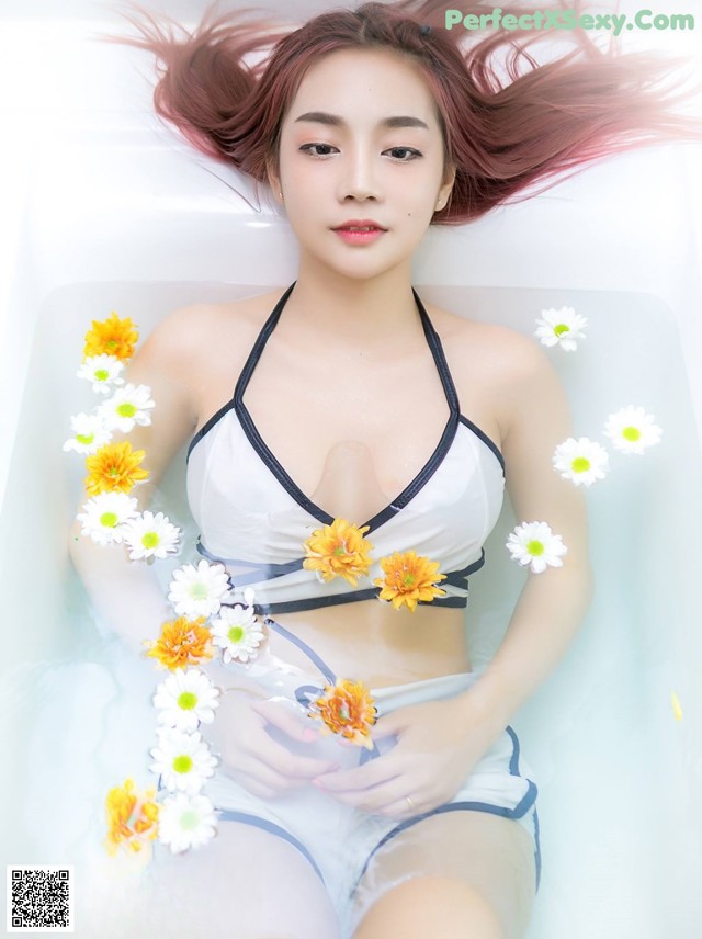 A woman in a bathtub with flowers in her hair.