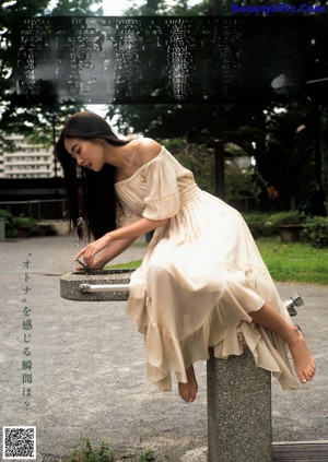 A woman in a white shirt and black skirt walking down a sidewalk.