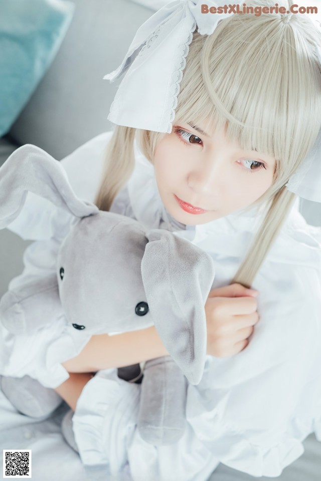 A woman in a white dress holding a stuffed animal.