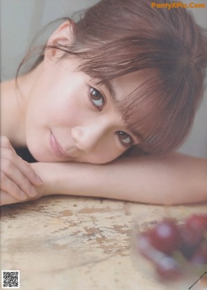 A woman with long brown hair leaning against a wall.