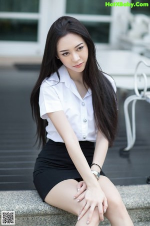 A woman in a white shirt and black skirt posing for a picture.