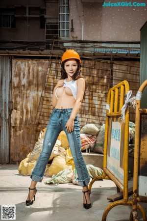 A woman wearing a hard hat standing in front of a building.