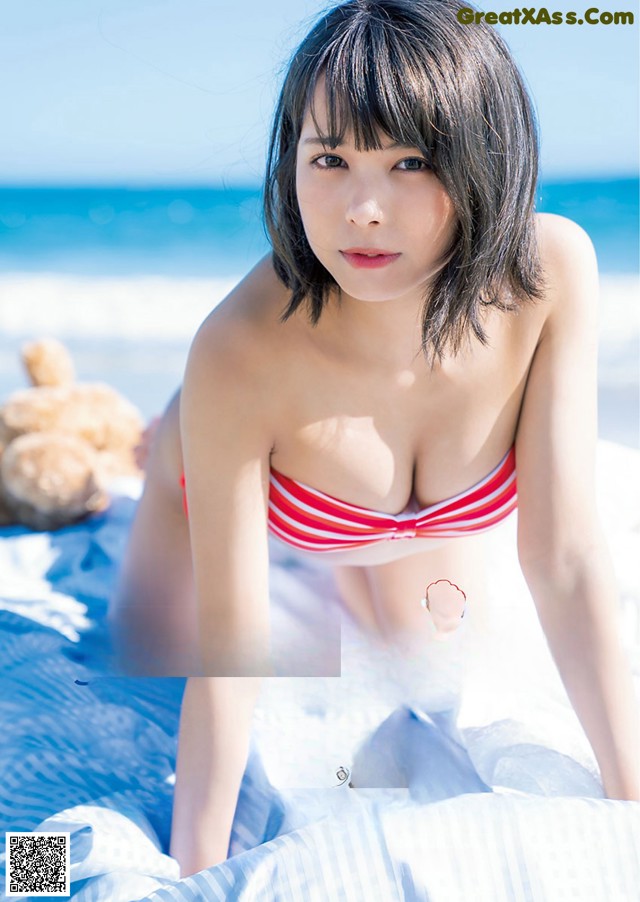 A woman in a red and white striped bikini laying on a beach.