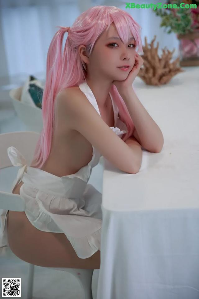 A woman with pink hair sitting at a table.