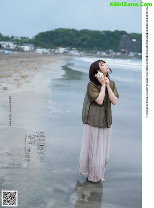 A woman standing on a beach next to the ocean.
