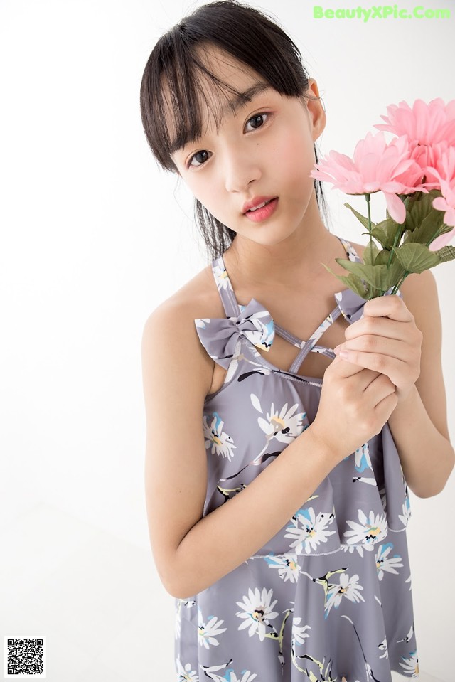 A young woman holding a bunch of pink flowers.