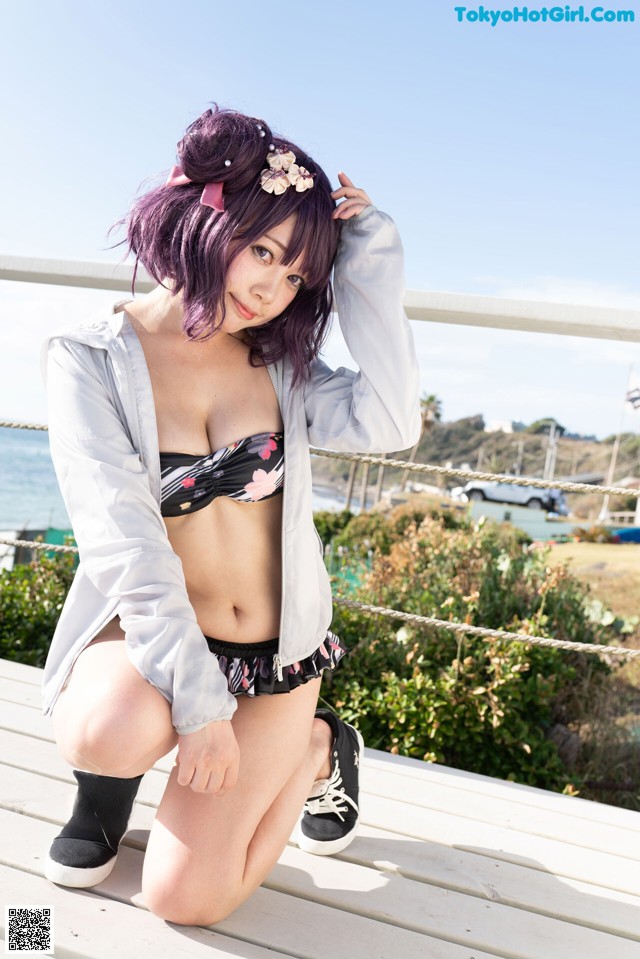 A woman in a bikini sitting on a wooden bench.