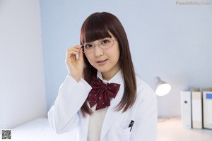 A woman in a white lab coat holding her glasses up to her face.