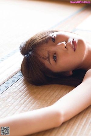 A woman laying on a tatami mat in a room.