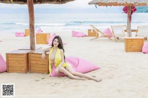 A woman in a yellow bathing suit sitting on a pink bean bag.