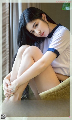 A woman in a white bathing suit sitting on the floor.